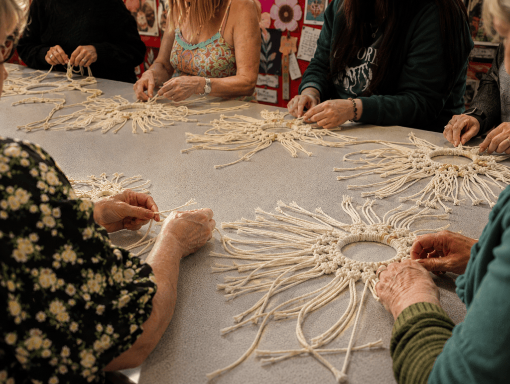 People making macramé pieces together around a table during a creative workshop.